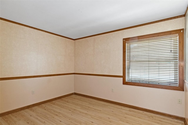 spare room with crown molding, light wood-style floors, and baseboards