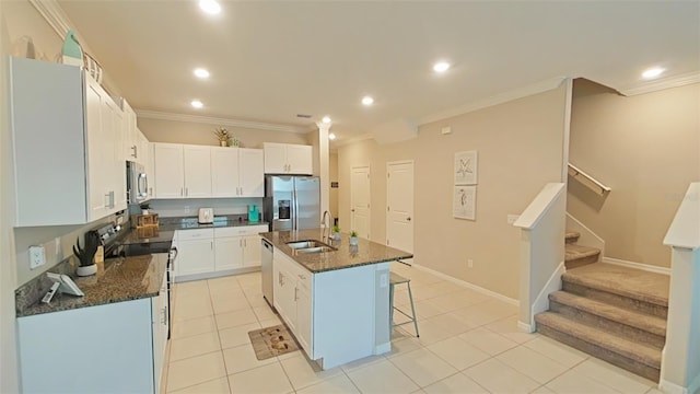 kitchen with a center island with sink, light tile patterned floors, stainless steel appliances, sink, and white cabinetry