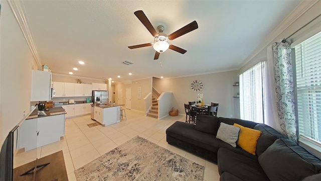 living room featuring ceiling fan, ornamental molding, and light tile patterned floors