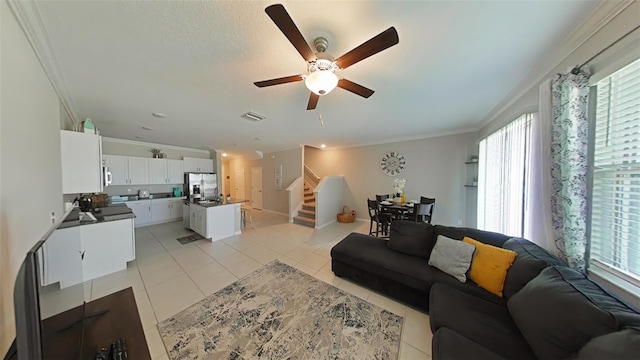 living room featuring crown molding, light tile patterned floors, and ceiling fan