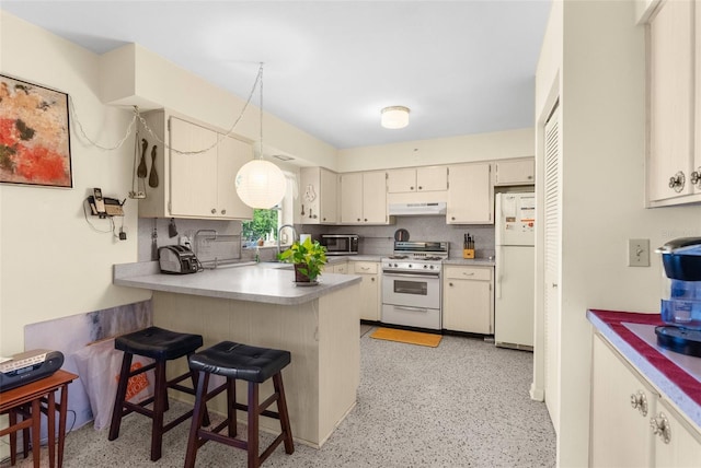 kitchen with white appliances, kitchen peninsula, a kitchen bar, and tasteful backsplash