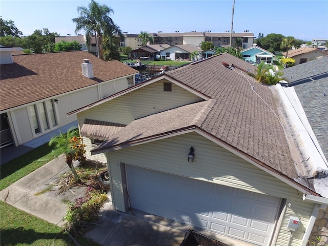 exterior space featuring a residential view, roof with shingles, driveway, and an attached garage