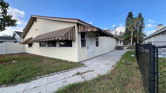 view of side of home with a yard and central AC