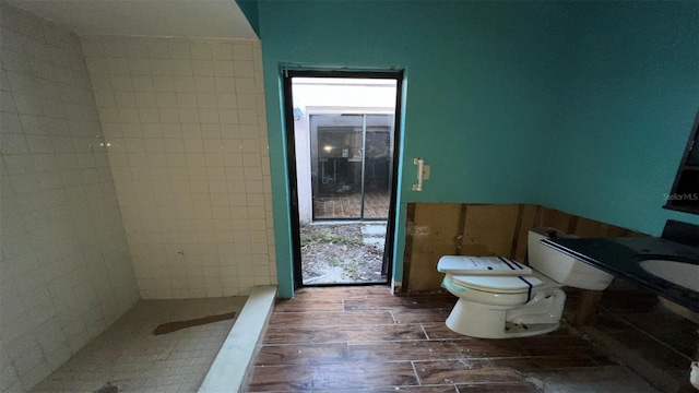 bathroom featuring toilet, hardwood / wood-style floors, and tiled shower