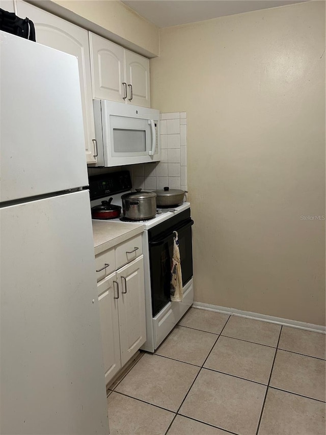 kitchen featuring light tile patterned floors, white appliances, white cabinetry, and tasteful backsplash