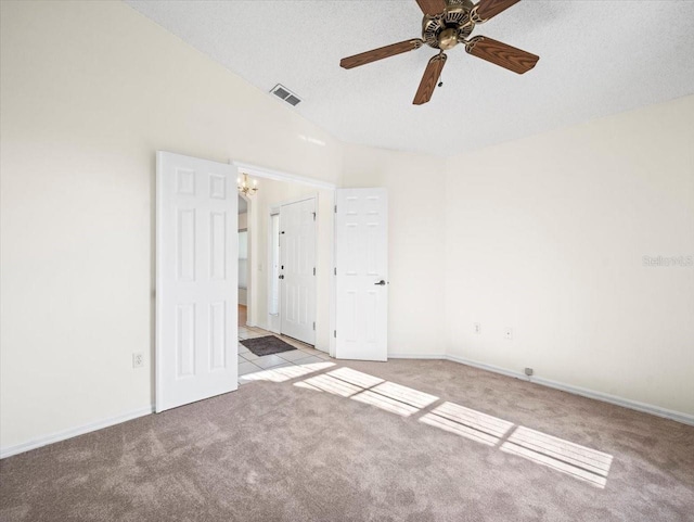 unfurnished bedroom with a textured ceiling, vaulted ceiling, ceiling fan, and light colored carpet