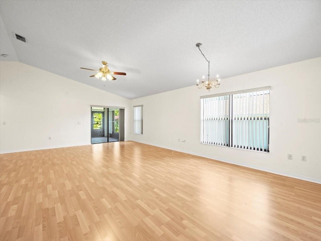 empty room with a textured ceiling, ceiling fan with notable chandelier, vaulted ceiling, and light hardwood / wood-style flooring