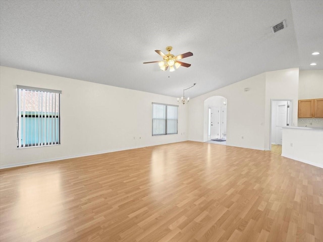 unfurnished living room featuring ceiling fan with notable chandelier, light hardwood / wood-style floors, and a textured ceiling