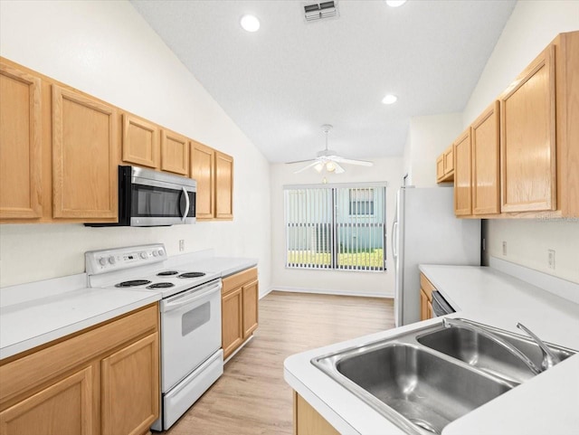 kitchen with light wood-type flooring, sink, vaulted ceiling, white appliances, and ceiling fan