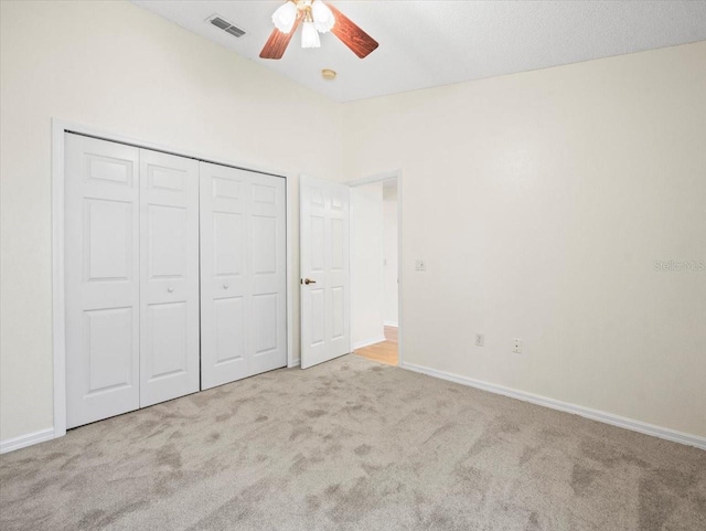 unfurnished bedroom featuring ceiling fan, a closet, and light carpet