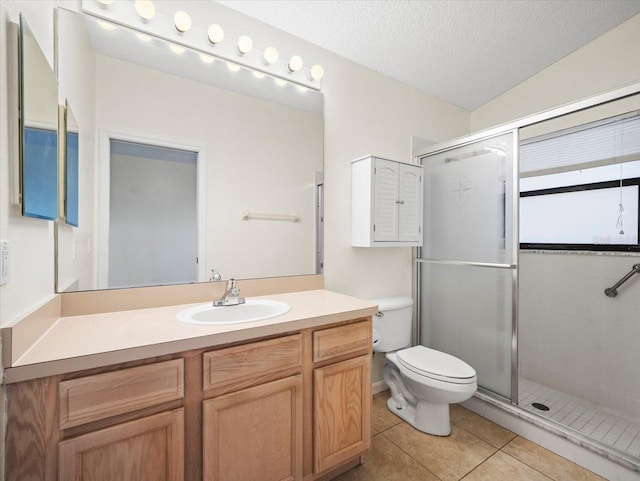 bathroom with a textured ceiling, walk in shower, tile patterned floors, vanity, and toilet