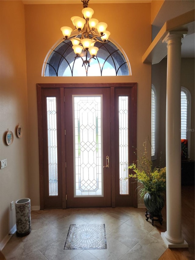 foyer entrance featuring decorative columns and a notable chandelier