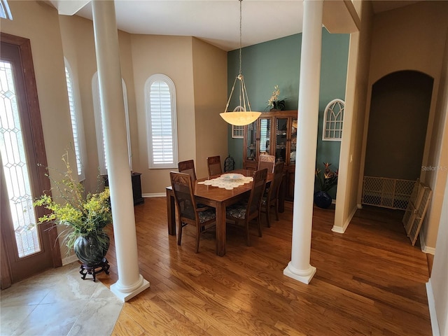 dining space featuring wood-type flooring and decorative columns