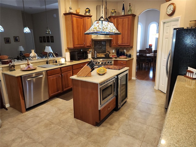 kitchen with a kitchen island, decorative light fixtures, beverage cooler, appliances with stainless steel finishes, and sink