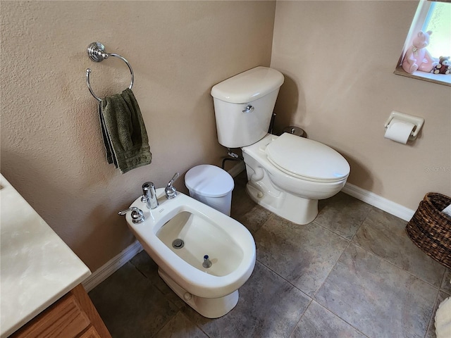 bathroom with a bidet, vanity, toilet, and tile patterned flooring