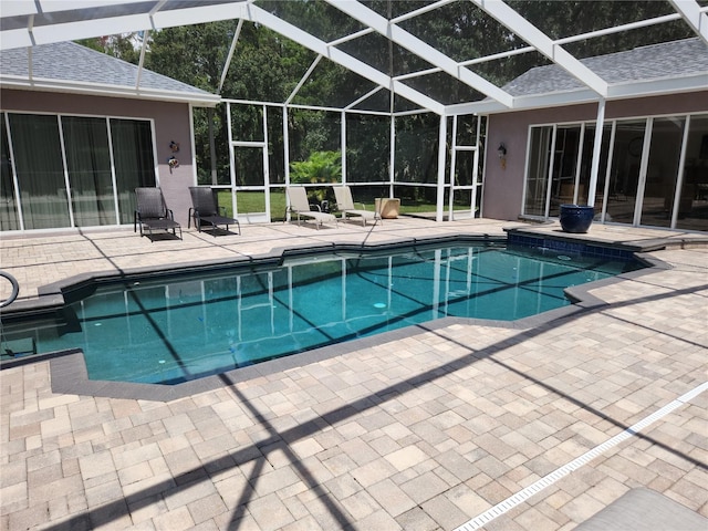 view of pool with glass enclosure and a patio