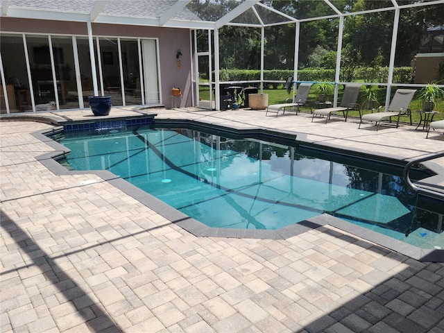 view of pool featuring glass enclosure and a patio