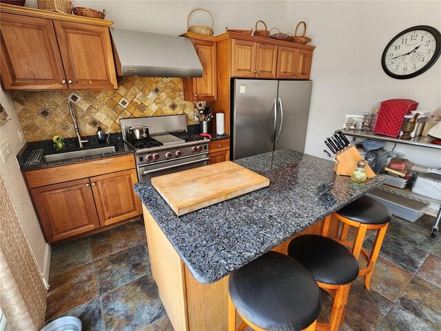 kitchen featuring wall chimney exhaust hood, a breakfast bar area, stainless steel appliances, and decorative backsplash