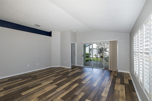 empty room featuring a textured ceiling, vaulted ceiling, and dark hardwood / wood-style floors