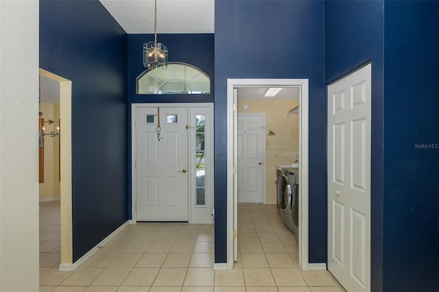 foyer entrance with a textured ceiling, an inviting chandelier, a towering ceiling, independent washer and dryer, and light tile patterned floors