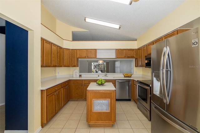 kitchen with a textured ceiling, light tile patterned flooring, a center island, and stainless steel appliances