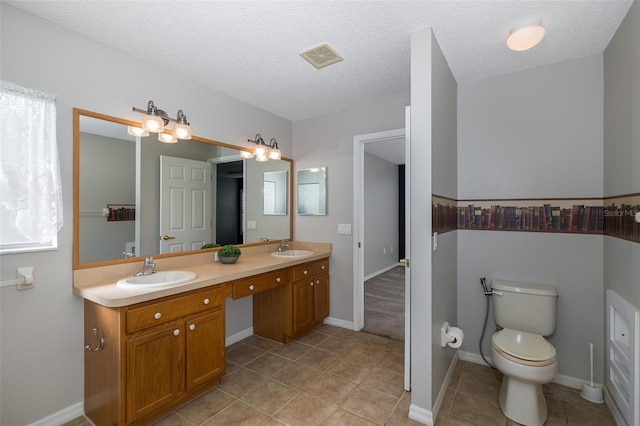 bathroom with tile patterned floors, a textured ceiling, vanity, and toilet