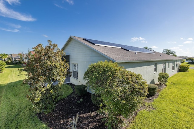 view of side of property featuring a lawn and solar panels