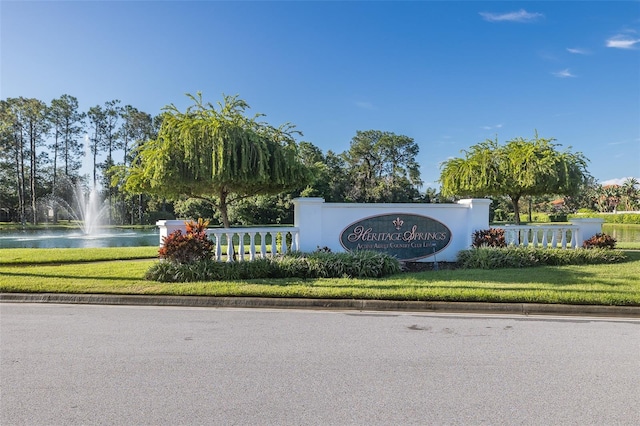 community sign with a water view and a yard