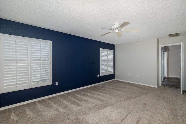 empty room featuring ceiling fan, carpet floors, and a textured ceiling