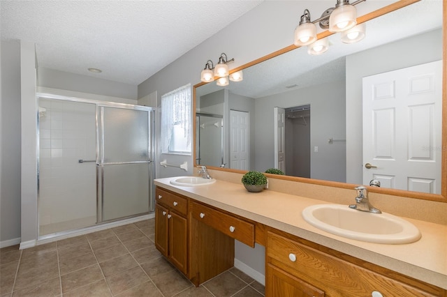 bathroom featuring a textured ceiling, vanity, tile patterned floors, and an enclosed shower