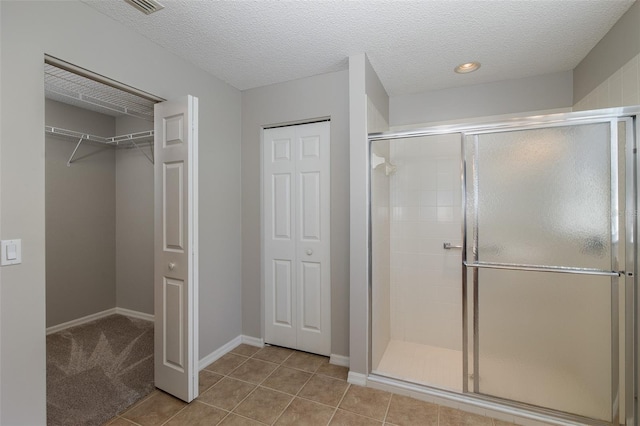 bathroom featuring a textured ceiling, an enclosed shower, and tile patterned floors