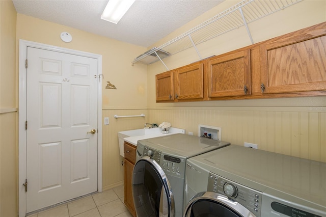 clothes washing area featuring cabinets, light tile patterned floors, washer and dryer, and a textured ceiling