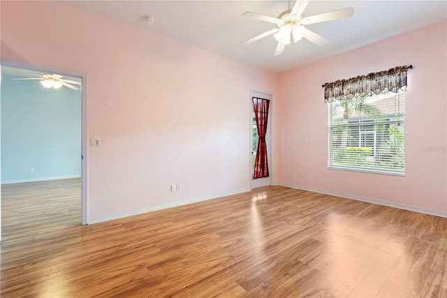 spare room featuring ceiling fan, light wood finished floors, and baseboards