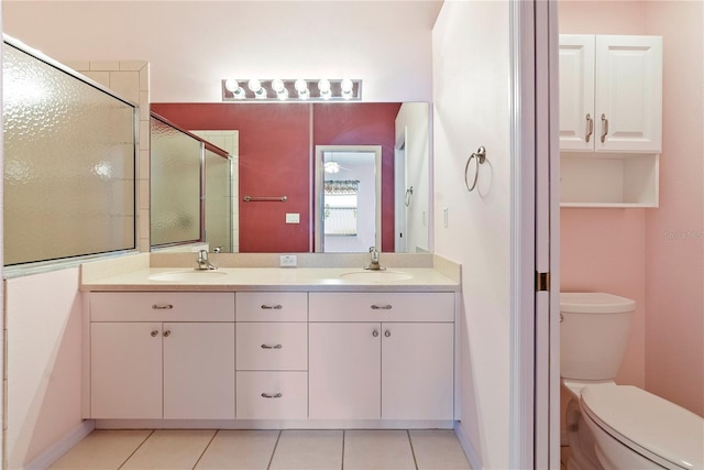 bathroom with a stall shower, tile patterned flooring, a sink, and toilet