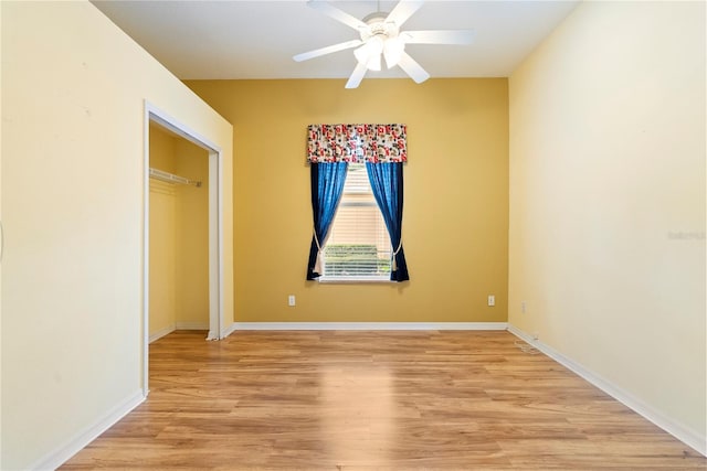 unfurnished bedroom featuring light wood-style floors, a closet, baseboards, and a ceiling fan