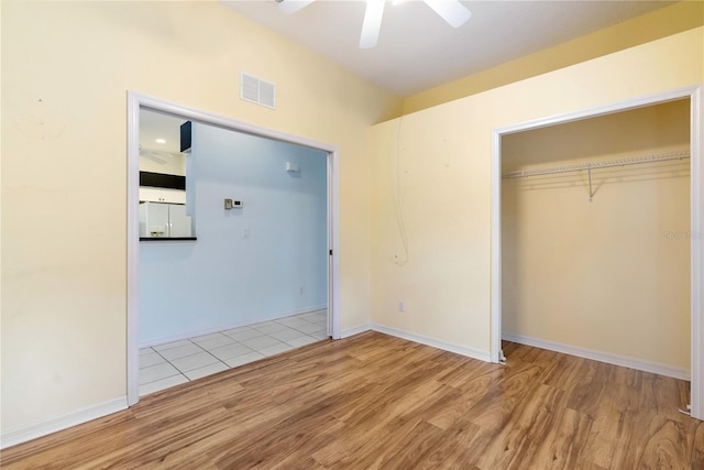 unfurnished bedroom featuring ceiling fan, visible vents, a closet, and wood finished floors