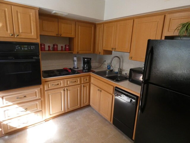 kitchen featuring light tile patterned floors, sink, backsplash, and black appliances