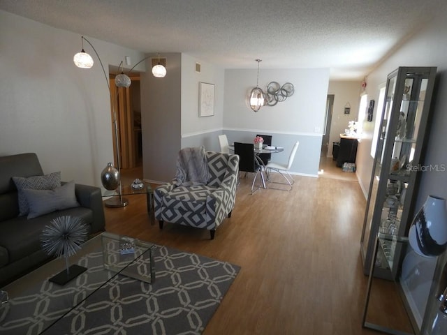 living room featuring a textured ceiling, a notable chandelier, and hardwood / wood-style flooring