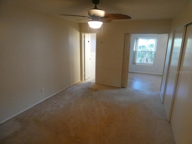 empty room featuring ceiling fan and light colored carpet