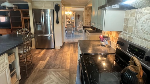 kitchen featuring decorative backsplash, wall chimney exhaust hood, stainless steel appliances, hardwood / wood-style flooring, and hanging light fixtures