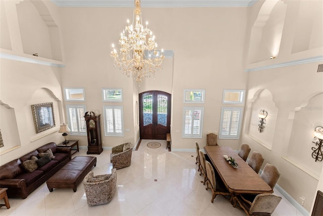 foyer entrance with arched walkways, french doors, a high ceiling, a chandelier, and baseboards