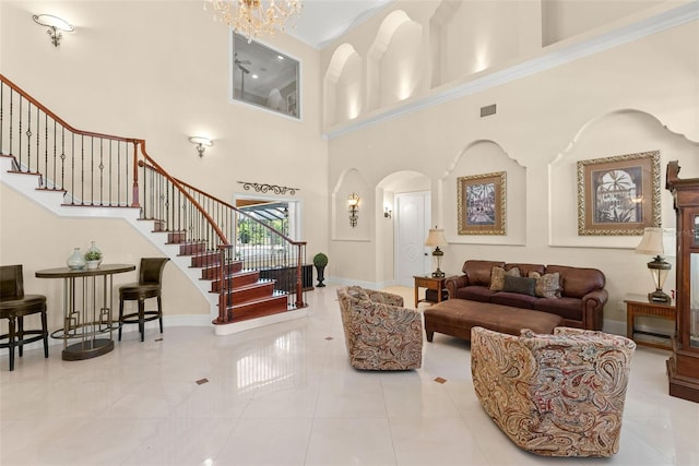 living room with arched walkways, visible vents, baseboards, stairway, and an inviting chandelier