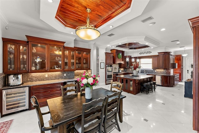 dining space featuring beverage cooler, ornamental molding, a raised ceiling, and visible vents