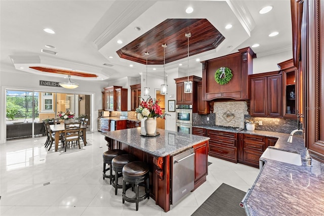 kitchen featuring ornamental molding, a raised ceiling, decorative backsplash, and a center island