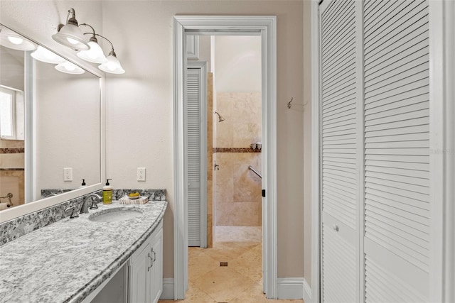 full bathroom with tiled shower, a closet, vanity, and baseboards