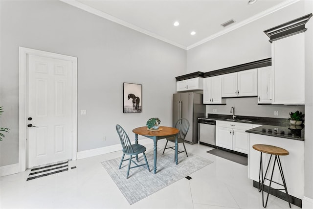 kitchen featuring visible vents, dark countertops, stainless steel appliances, crown molding, and a sink