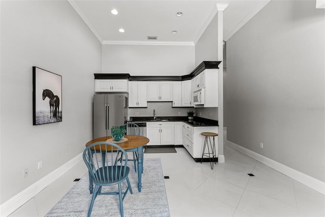 kitchen with appliances with stainless steel finishes, crown molding, a sink, and baseboards