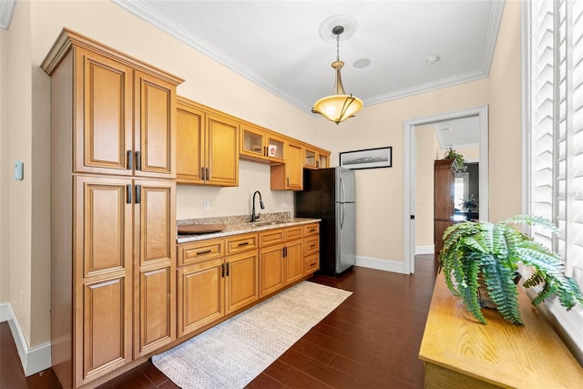 kitchen featuring a sink, freestanding refrigerator, dark wood-style floors, decorative light fixtures, and crown molding