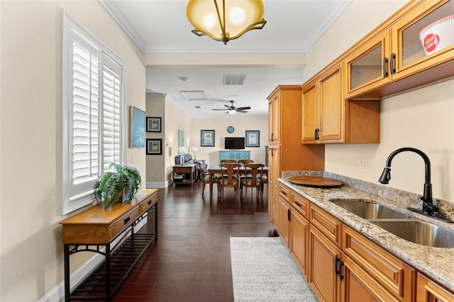 kitchen featuring wood finished floors, a sink, visible vents, ornamental molding, and light stone countertops