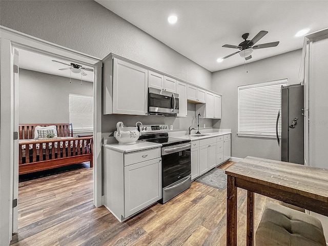 kitchen with light wood finished floors, ceiling fan, stainless steel appliances, light countertops, and a sink